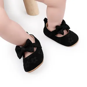 Primer plano de zapatos de encaje negro para bebé con lazo grande y motivos de flores