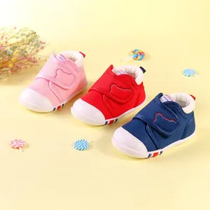Close-up view of cute toddler walking shoes in pink, red, and navy blue with bear detail