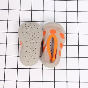 Close-up of toddler sock shoes showing non-slip sole and breathable orange polka dot knit