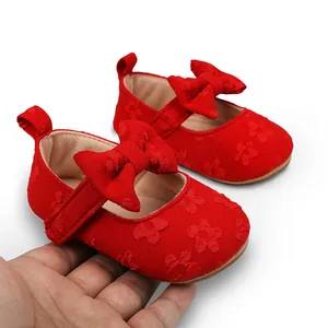 Detalle de zapatos de princesa rojos para bebé con flores de encaje y un lazo decorativo