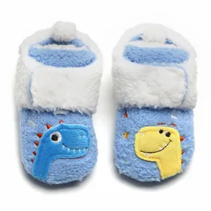 Detailopname van pluche baby-winterschoenen met dinosaurusborduursel