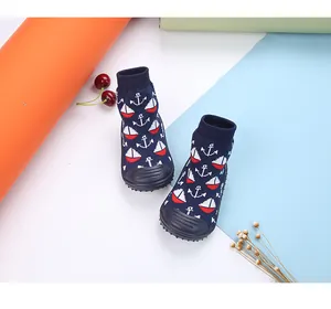 Top-down view of navy baby sock shoes with nautical anchor and sailboat patterns.