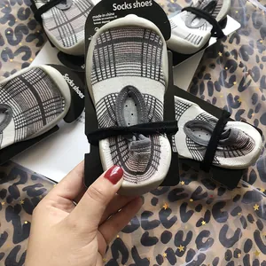Nahaufnahme von karierten Kleinkindsockenschuhen mit grauen Gummisohlen und Halteband.