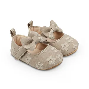 Vista detallada de zapatos de princesa para bebé beige con bordado floral y detalle de lazo