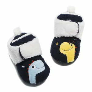 Detailopname van marineblauwe babywinterschoentjes met schattig dinosaurusborduurwerk.