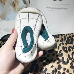 Close-up view of soft-soled baby sock shoes with grey check patterns.