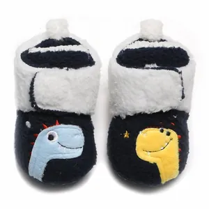 Detailweergave van pluche marineblauwe baby loopschoentjes met schattig dinosaurus borduursel.