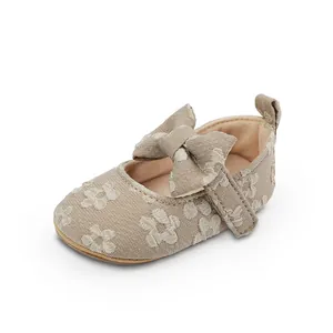 Vista detallada de zapato beige para bebé niña con motivo floral y lazo decorativo