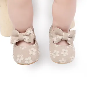 Primer plano de zapatos para bebé de encaje floral beige con un gran lazo para caminar