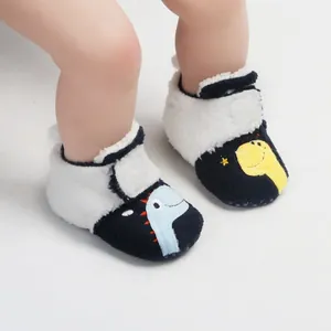 Detailopname van winterse babyloopschoentjes met dinosaurusontwerpen en pluche.