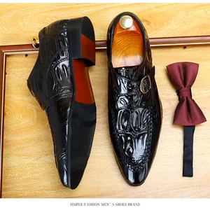 Dettaglio di scarpe da uomo in pelle nera con motivo a coccodrillo e fibbia laterale.