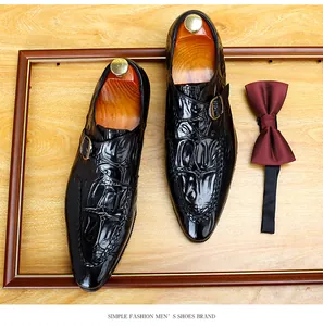 Dettaglio scarpe eleganti uomo in pelle nera motivo coccodrillo con fibbia metallica
