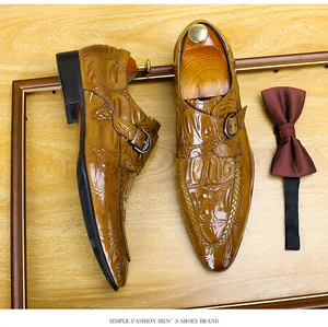 Primo piano di scarpe monk marroni da uomo con motivo a coccodrillo e bordo intrecciato.