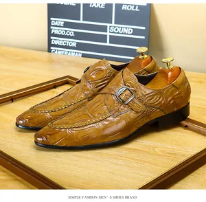 Primo piano di scarpe da uomo in pelle marrone con motivo a coccodrillo e fibbia.