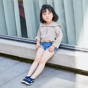 Little girl wearing navy blue polka dot breathable soft-sole toddler sock shoes outdoors