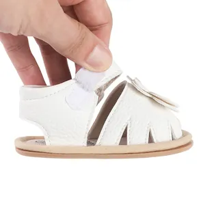 Détail d'une sandale d'été blanche pour bébé avec fleur et bride velcro réglable