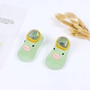 Close-up of green baby walker shoes with cute cartoon duck face and soft sole.