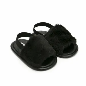Close-up of soft black fuzzy faux fur baby sandals with an elastic ankle strap.