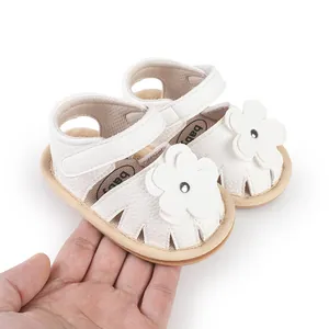 Close-up of white infant walking shoes with flower detail and soft sole