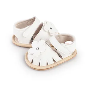 Close-up of white baby walking shoes with delicate flower decoration and leather texture