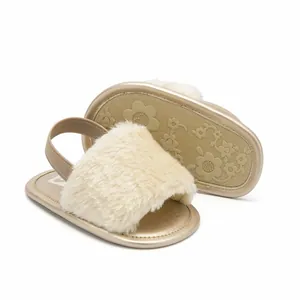 Detail view of cream fluffy baby sandals with metallic gold soles and elastic straps.
