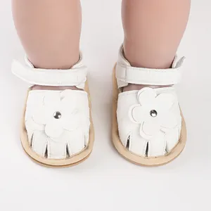 Close-up of white baby walking shoes featuring a faux leather flower and soft sole.