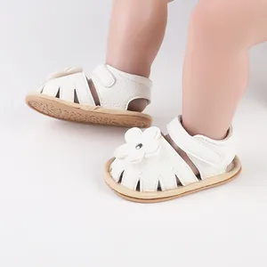 Detailed view of white baby walking sandals with flower decoration and Velcro strap