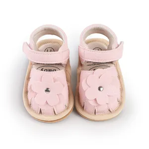 Close-up of pink baby pre-walker sandals with decorative flower and velcro strap