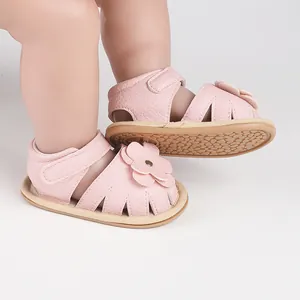 Close-up of pink baby walking sandals with decorative flower and textured leather.