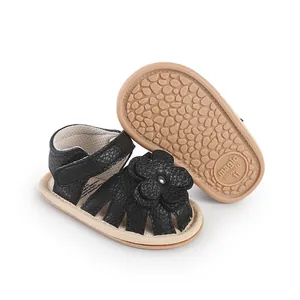 Close-up detail of black baby prewalker sandals featuring a flower and textured non-slip sole