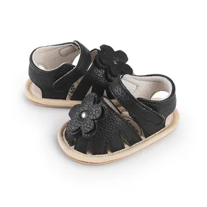 Detail view of black faux leather baby walking sandals featuring a soft flower decoration
