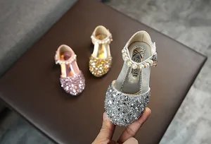 Detail von silbernen glitzernden Mädchen-Prinzessin-Schuhen mit Perlenriemen.