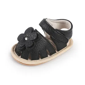 Close-up of black baby pre-walker sandals with a decorative flower and Velcro strap.