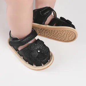 Close-up of black infant walking sandals with flower decoration and non-slip rubber sole