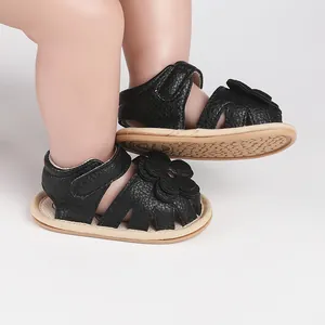 Detailed view of black baby sandals with decorative flower and textured leather