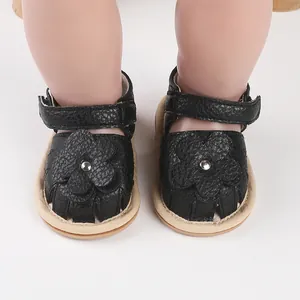 Close-up view of black leather baby sandals with floral applique and velcro strap.