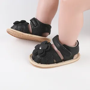 Detailed view of black baby walking sandals featuring flower design and velcro straps
