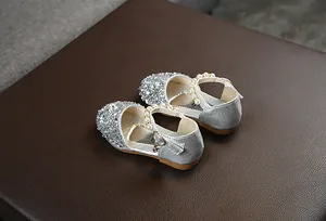 Detailansicht funkelnder silberner Mädchen-Prinzessinenschuhe mit Perlenriemen.