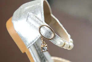 Detailansicht silberner Glitzer-Prinzessinnenschuh für Mädchen mit Perlenriemen.
