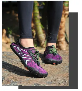 Primo piano di scarpe da scoglio viola a cinque dita con lacci verdi su una roccia.