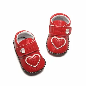 Gros plan de chaussures de marche rouges pour bébé avec cœur blanc et velcro