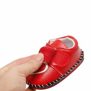 Détail de chaussures de marche pour bébé à semelle souple rouge avec patte auto-grippante