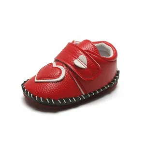 Gros plan sur chaussure bébé rouge à semelle souple et motifs cœurs blancs