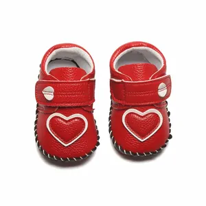 Vue détaillée de chaussures de marche rouges pour bébé avec un joli motif cœur blanc