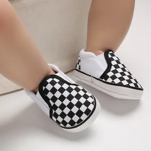 Close-up of black and white checkerboard baby walking shoes with soft white soles.