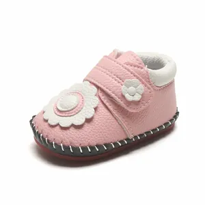 Gros plan détaillé de chaussures de marche roses pour bébé avec fleur décorative.