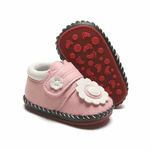 Vue détaillée de chaussures roses pour bébé avec fleur blanche et semelles antidérapantes