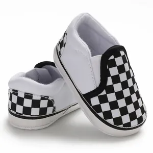 Close-up of baby canvas shoes with black and white checkered pattern and soft sole.