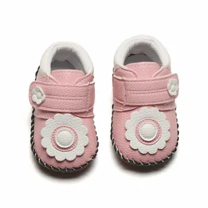 Vue détaillée de chaussures bébé roses avec décoration de fleurs blanches et semelle
