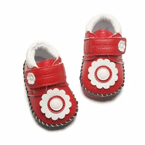 Détail de chaussures de marche rouges pour bébé avec fleurs blanches et velcro